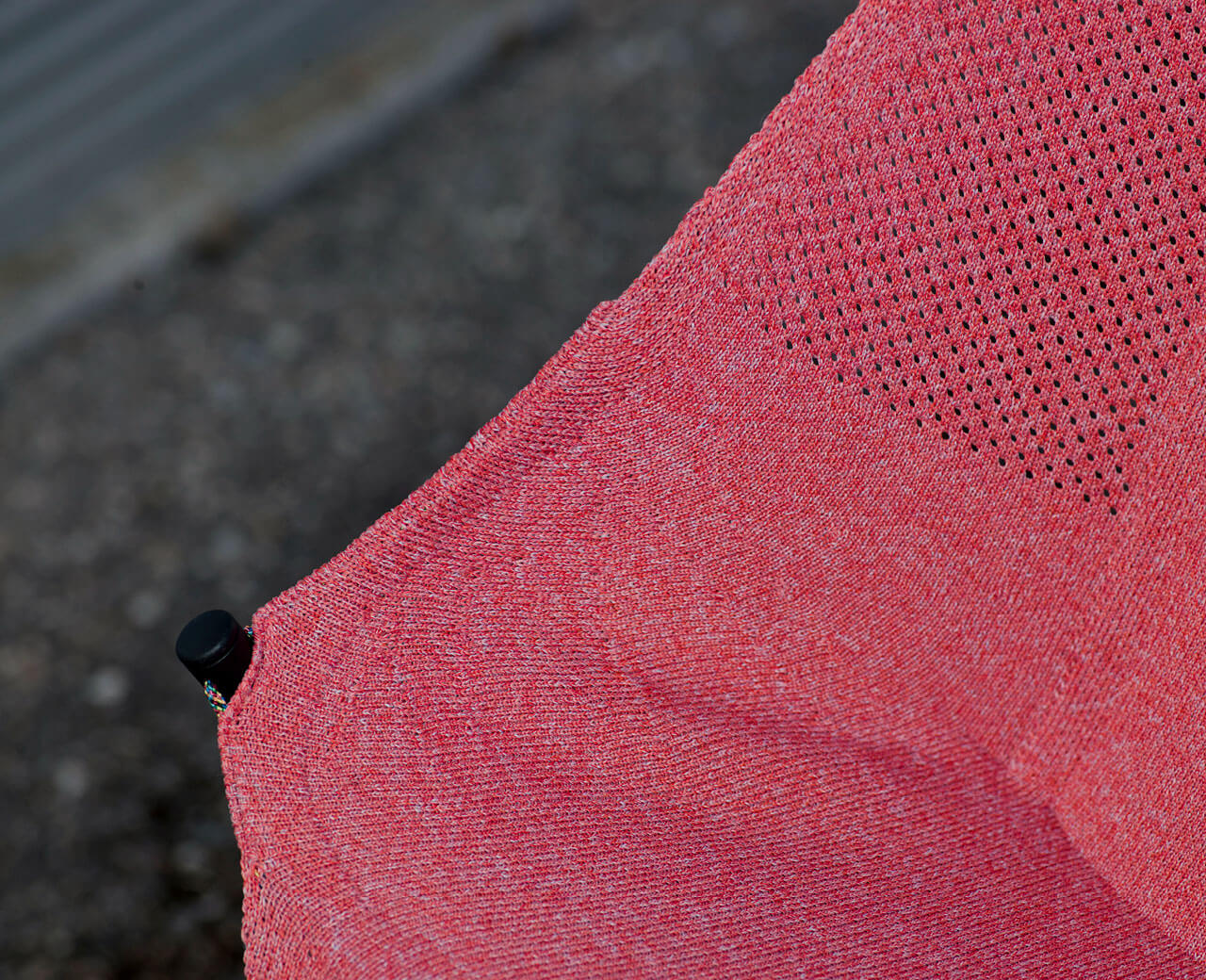 Detail of a red 3D knitted stroller mesh with embedded straps and hooks for reduced mounting effort